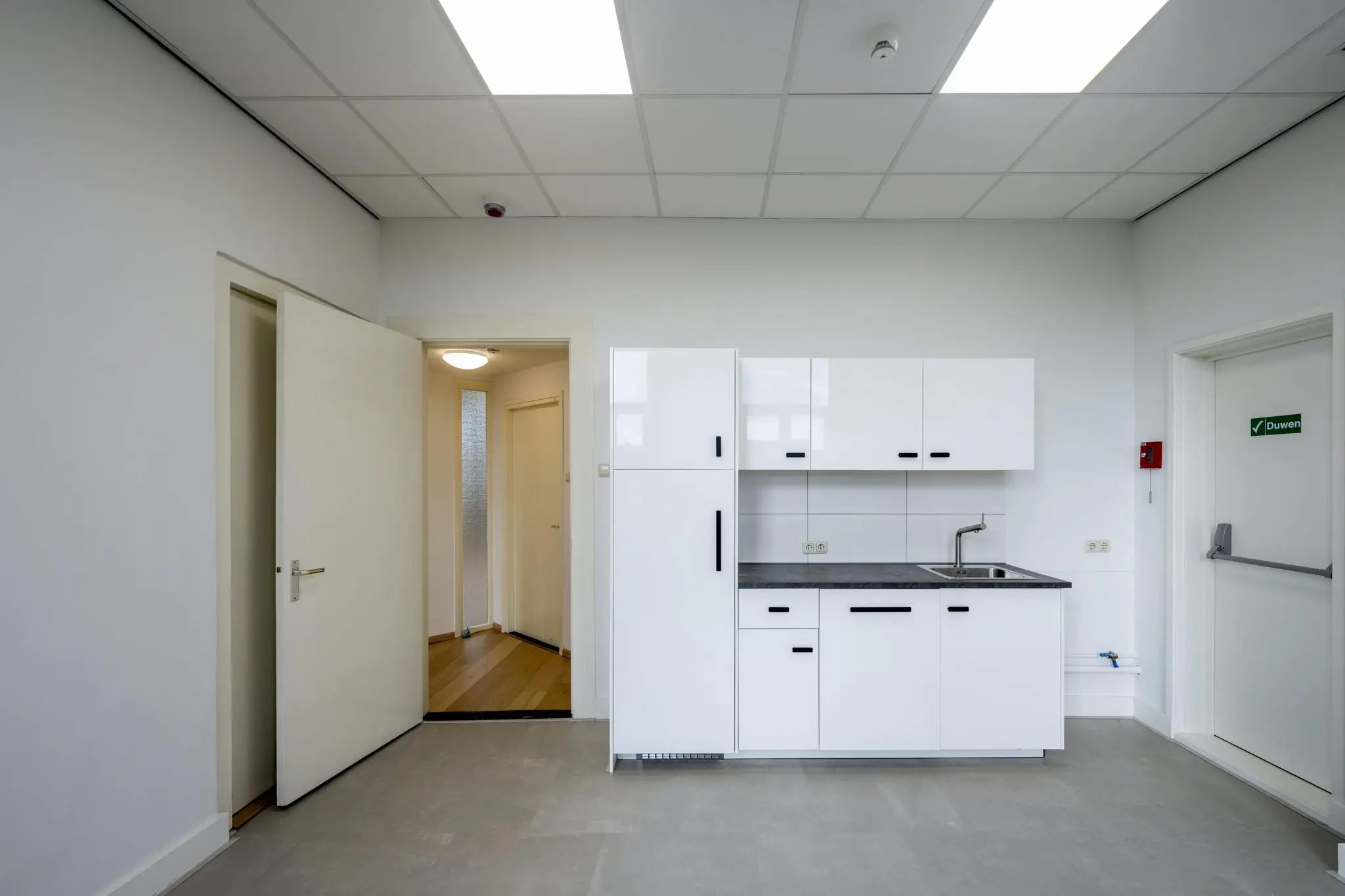 Moderne, witte kitchenette in een strakke, lichte ruimte aan de Nieuwe Gracht.